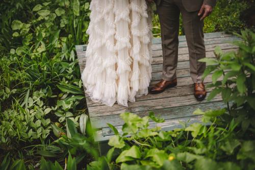 A Western MA Wedding Photographer captures a bride and groom standing on a wooden bridge in the woods.