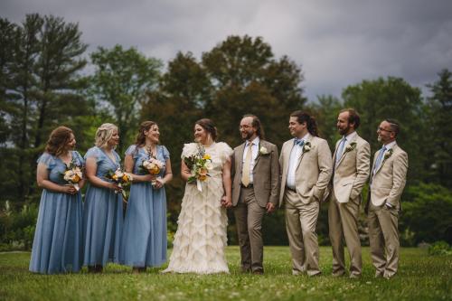 A group of bridesmaids and groomsmen standing in a field captured by a Western MA Wedding Photographer.