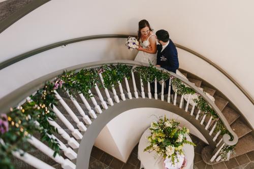A man and woman standing on a spiral staircase captured beautifully by a Western MA Wedding Photographer.