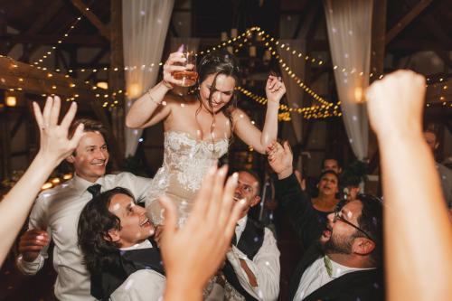 As a Western MA wedding photographer, I capture unforgettable moments like when a bride is joyfully lifted up by her friends at a wedding reception.