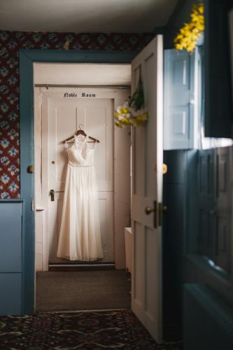 As a Western MA Wedding Photographer, I capture the beauty of special moments, such as a wedding dress elegantly hanging in a doorway.