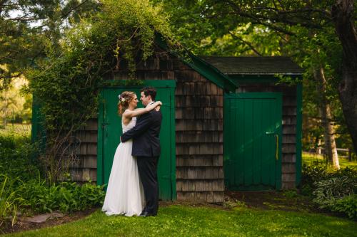The best wedding photography of 2023 captures a heartfelt moment as a bride and groom lovingly embrace in front of a green shed.