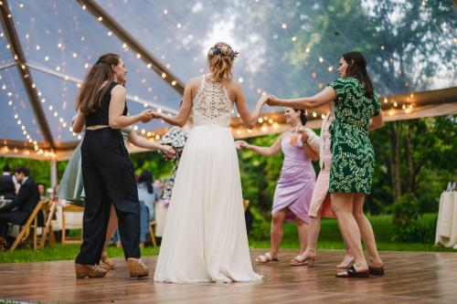 A Western MA Wedding Photographer capturing a bride and her bridesmaids dancing in a tent.
