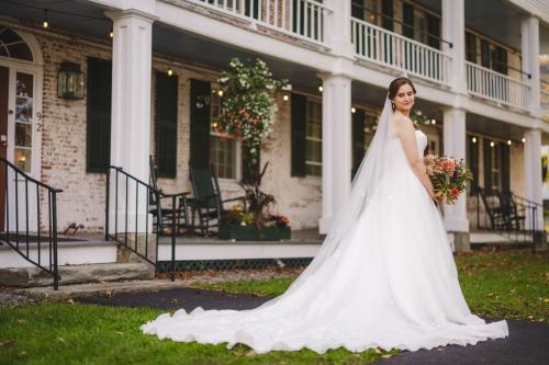 A Western MA Wedding Photographer capturing a beautiful bride standing in front of a white house.