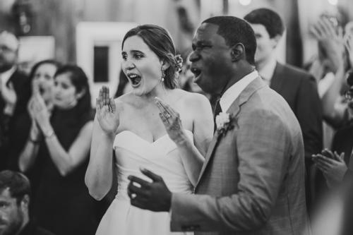 A Western MA Wedding Photographer captures a joyful moment of a bride and groom clapping at their wedding reception.