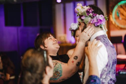 A Western MA Wedding Photographer captures a heartfelt moment as a man with a flower crown embraces a woman at a wedding.