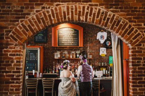A Western MA wedding photographer captures a bride and groom standing in front of a brick bar.