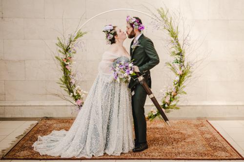 A Western MA wedding photographer captures a heartwarming moment of a bride and groom kissing in front of a floral wreath.