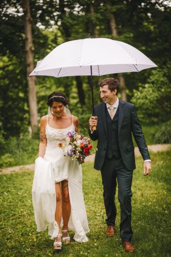 A Western MA Wedding Photographer captures a bride and groom walking under an umbrella.