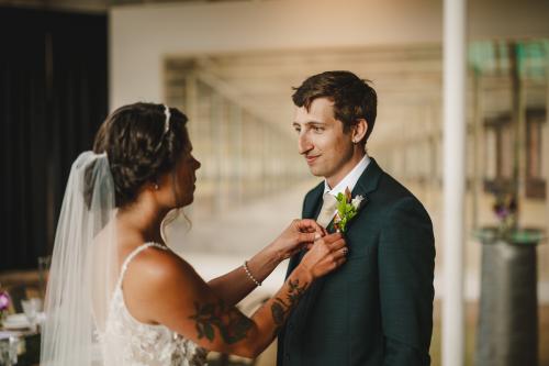 A Western MA wedding photographer captures a tender moment between a bride and groom as they adjust their boutonnieres.