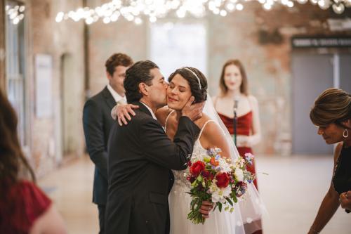 A Western MA Wedding Photographer captures the heartfelt moment as a bride kisses her groom during their wedding ceremony.