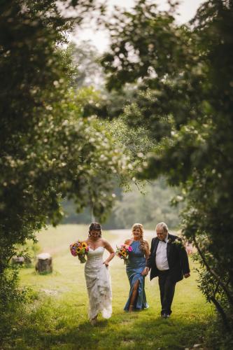 A Western MA Wedding Photographer captures a bride and groom walking through a picturesque wooded area.