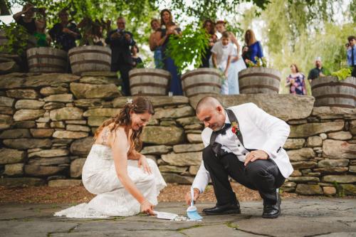 Western MA Wedding Photographer capturing a bride and groom joyfully writing their wedding vows on a stone wall.