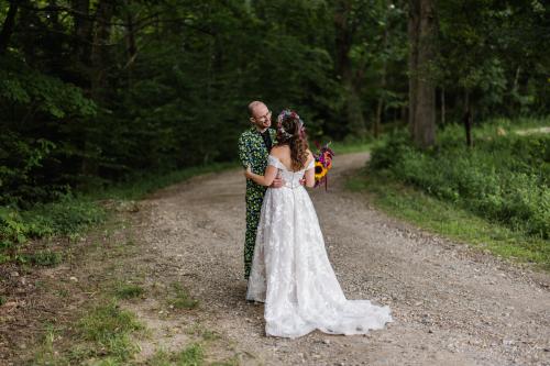 A Western MA Wedding Photographer captures a heartfelt moment of a bride and groom hugging on a dirt road in the woods.