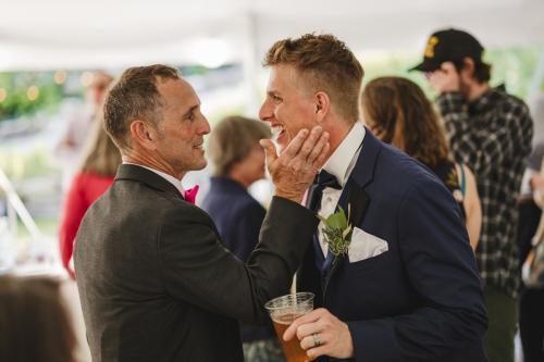 Western MA Wedding Photographer captures a heartwarming moment between two men as they exchange a tender kiss during their wedding reception.