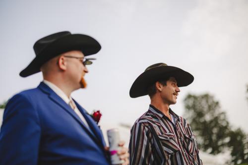 Two men in cowboy hats standing next to each other at a Western-themed wedding.