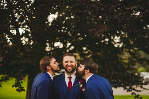 Three groomsmen laughing in front of a tree captured by a Western MA Wedding Photographer.