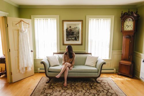 A woman sitting on a couch in a green room, captured beautifully by a Western MA Wedding Photographer.