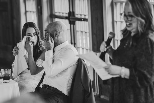 A bride, captured by a Western MA Wedding Photographer, wipes her eyes during her heartfelt wedding speech.