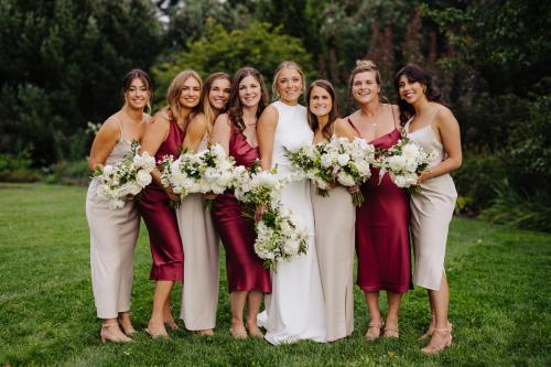 A group of women in beautiful dresses, capturing the essence of a wedding celebration, while elegantly holding vibrant flowers.