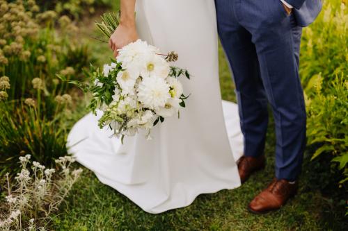 A stunning bride and groom in Western MA, captured by a talented wedding photographer, holding a bouquet amidst the beautiful garden setting.