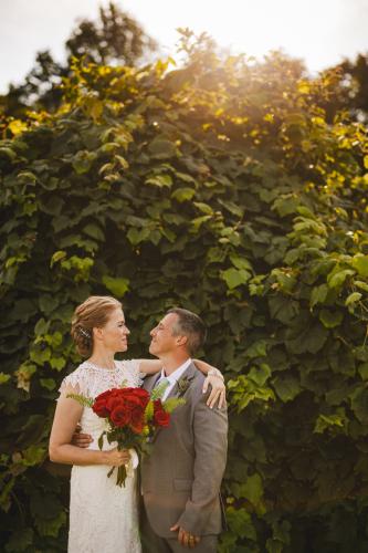 A Western MA Wedding Photographer captures a bride and groom standing in front of an ivy covered wall.