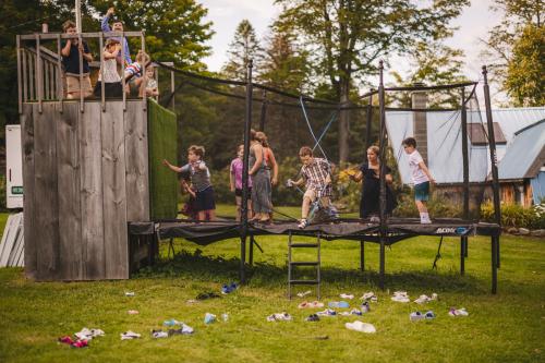 A group of people standing on a trampoline in a yard captured by a Western MA Wedding Photographer.
