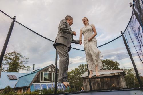 Wedding photography of a bride and groom joyfully bouncing on a trampoline.