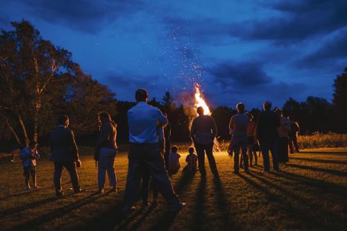 A group of people standing around a bonfire at night captured by a Western MA Wedding Photographer.