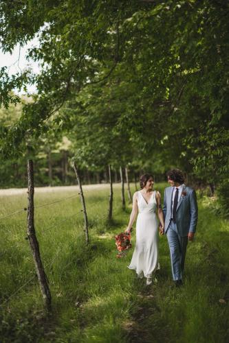 A Western MA Wedding Photographer captures a beautiful moment of a bride and groom walking down a path in a wooded area.