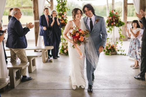 A Western MA Wedding Photographer captures a bride and groom walking down the aisle at a barn wedding.