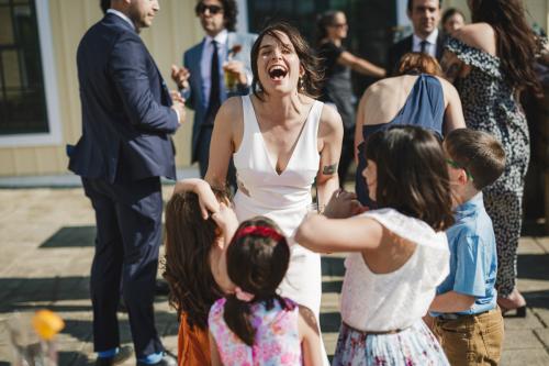 A Western MA Wedding Photographer captures moments of joy as a woman in a white dress laughs with children around her.