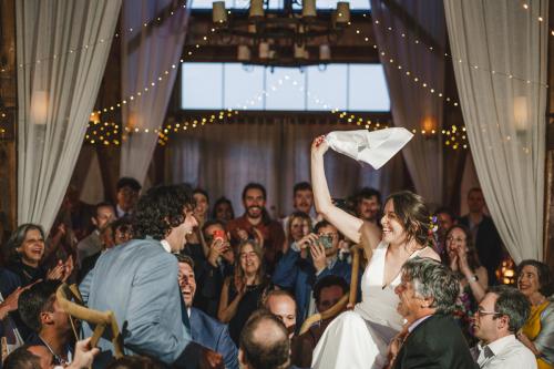 A Western MA Wedding Photographer captures a joyful moment where the bride and groom celebrate their nuptials by playfully throwing a towel in the air at their wedding reception.