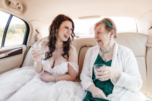 A Western MA Wedding Photographer captures the cherished moment of a bride and her mother sitting in the back seat of a car.
