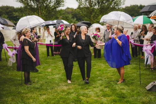 A group of women holding umbrellas in a grassy area. Perfect for your Western MA Wedding photographs.