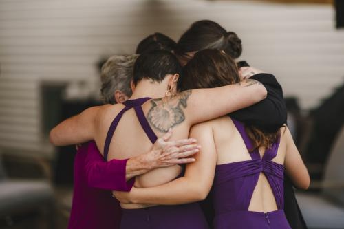 Western MA Wedding Photographer capturing bridesmaids hugging each other in purple dresses.