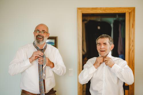 Two men tying their ties captured by a Western MA Wedding Photographer.