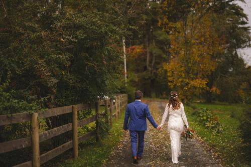 A bride and groom walking down a path in autumn captured by a talented Western MA Wedding Photographer.
